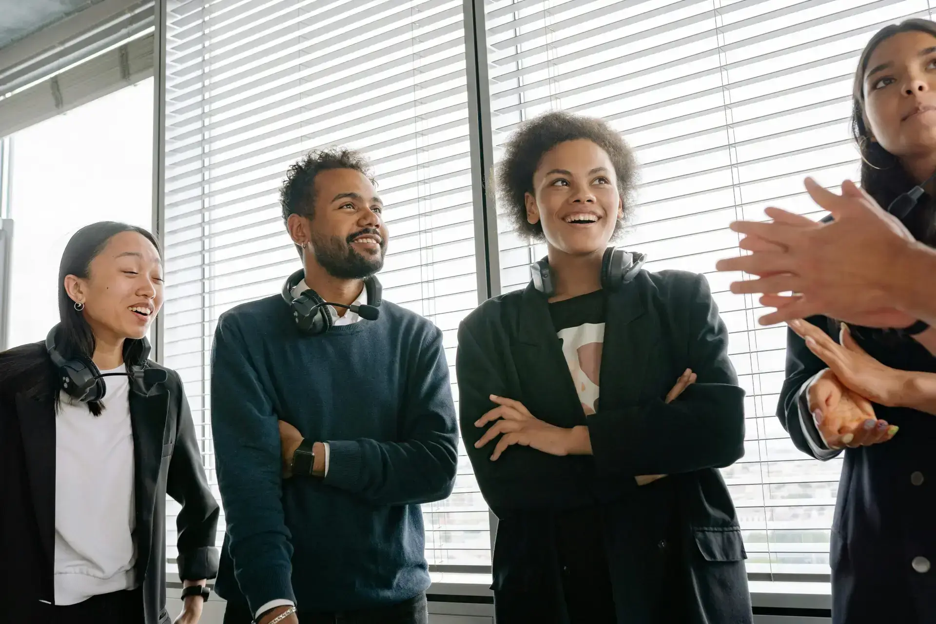 Group of diverse colleagues with headsets enjoying a conversation in a bright office setting.