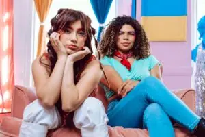 Two fashionable Gen Z friends relaxing indoors, embracing vibrant style and colorful aesthetics.
